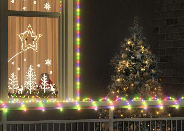 Väline jõulustseen, kus on kaunistatud puu kuldsete ehete ja tuledega akna kõrval, mis on raamitud mitmevärviliste tulukestega. Aknal on valgustatud kaunistused tähtede, lumehelveste ja puude kujul ning kõrvalaknal ripub pärg punase lindiga.